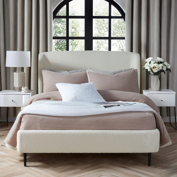 Neatly made bed with pillows and a blanket in a bedroom setting.