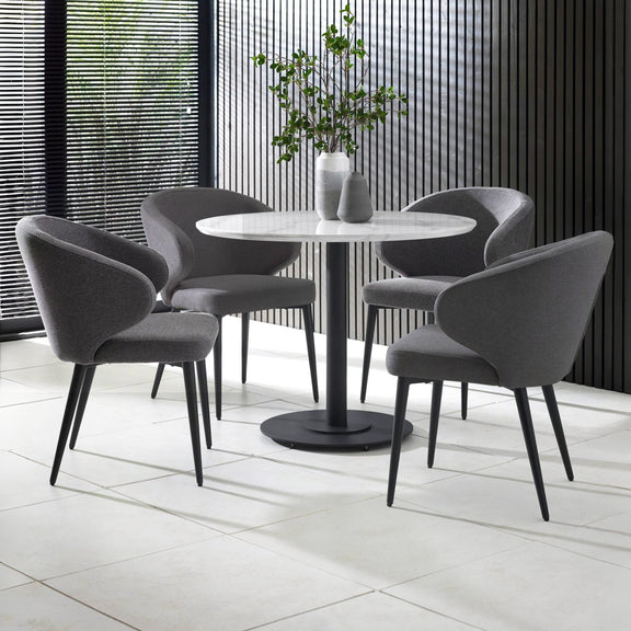 Dining area with round table and four gray chairs in a modern interior setting.