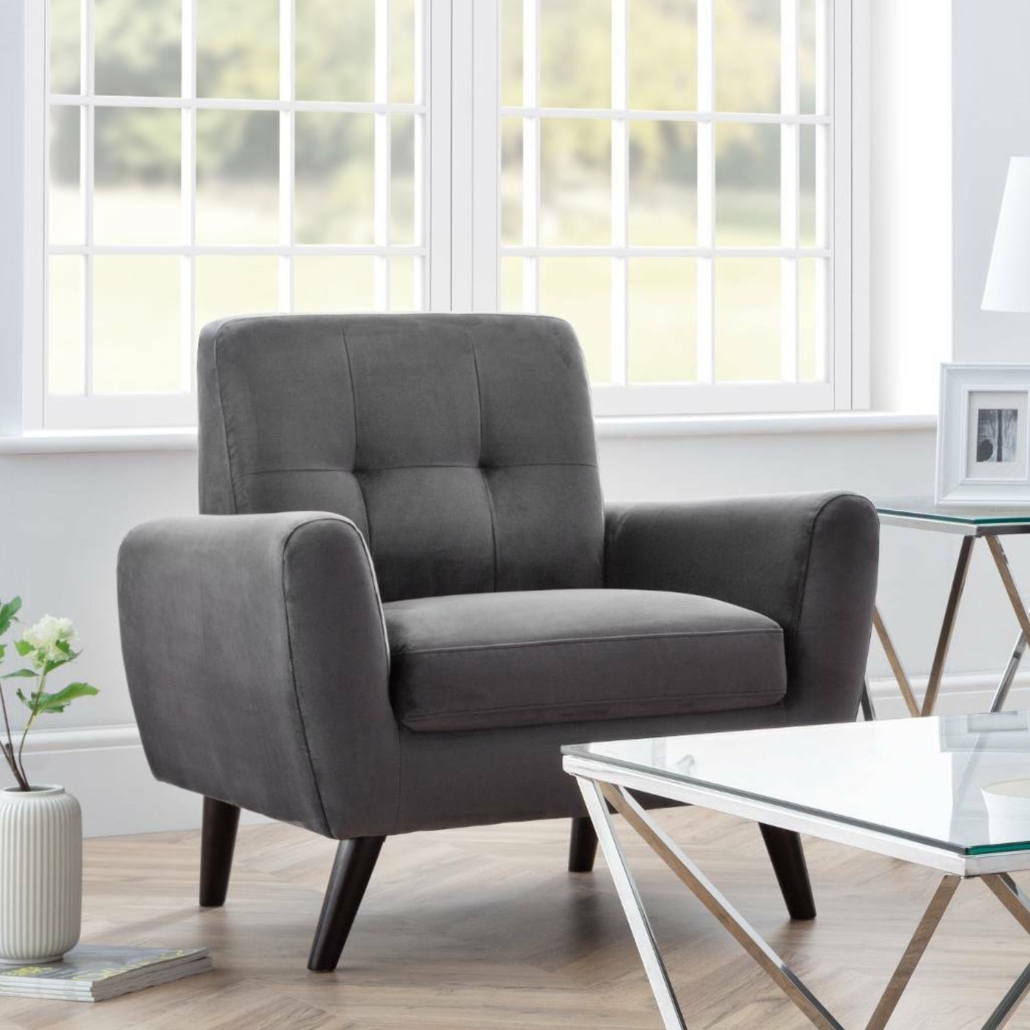 Gray armchair in a living room with a glass coffee table and decorative items.