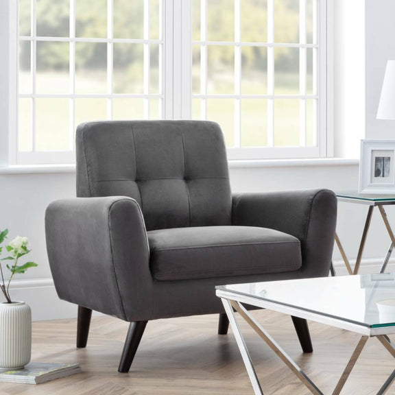 Gray armchair in a living room with a glass coffee table and decorative items.