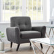 Gray armchair in a living room with a glass coffee table and decorative items.