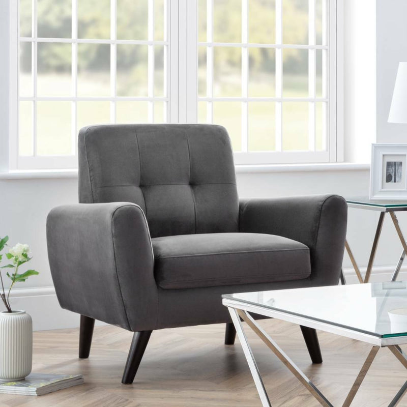 Gray armchair in a living room with a glass coffee table and decorative items.