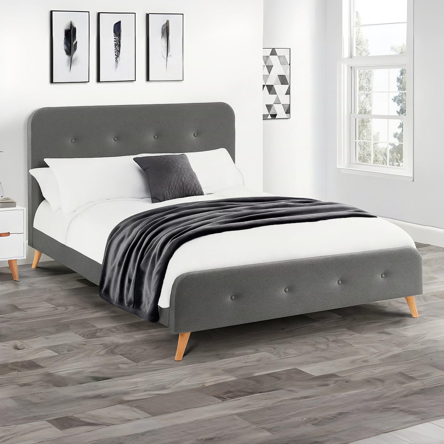 Gray upholstered bed with white bedding and a black blanket in a bedroom setting.