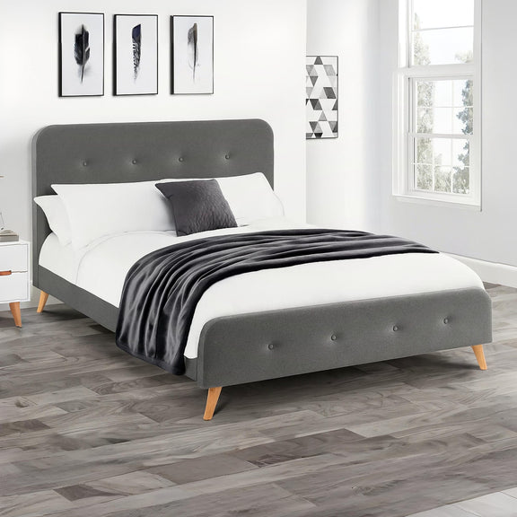 Gray upholstered bed with white bedding and a black blanket in a bedroom setting.