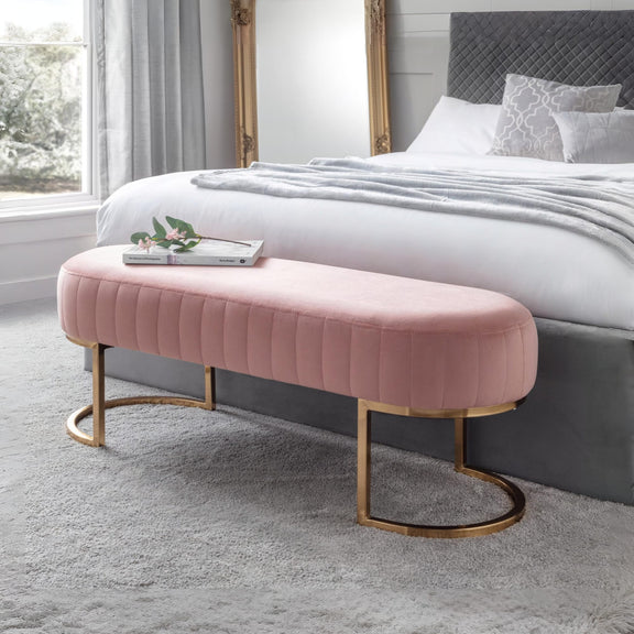 Pink ottoman with gold legs in a bedroom setting