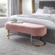 Pink ottoman with gold legs in a bedroom setting