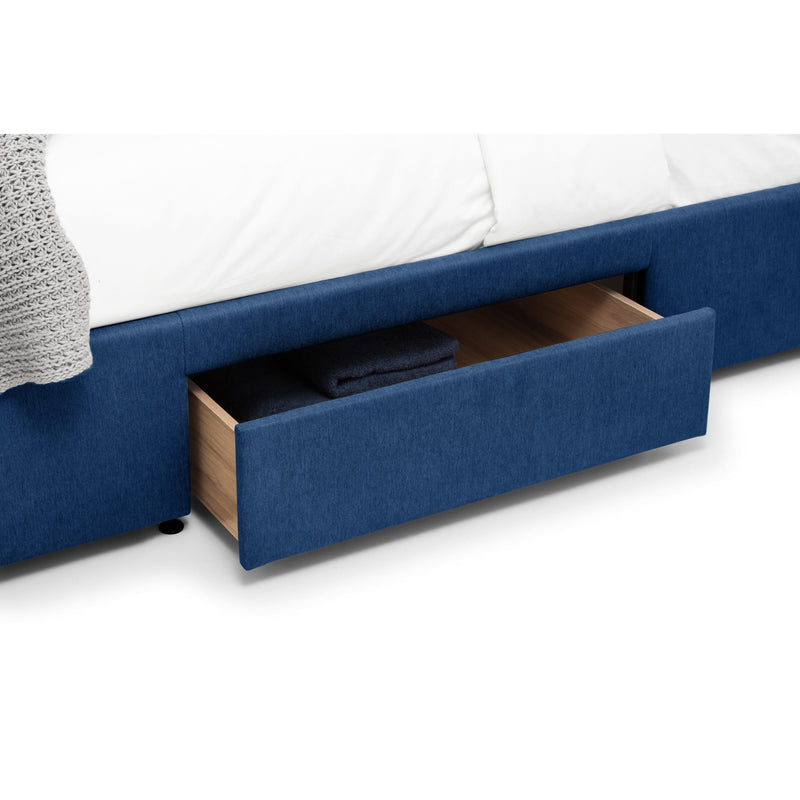 Blue upholstered bed with an open drawer on a white background