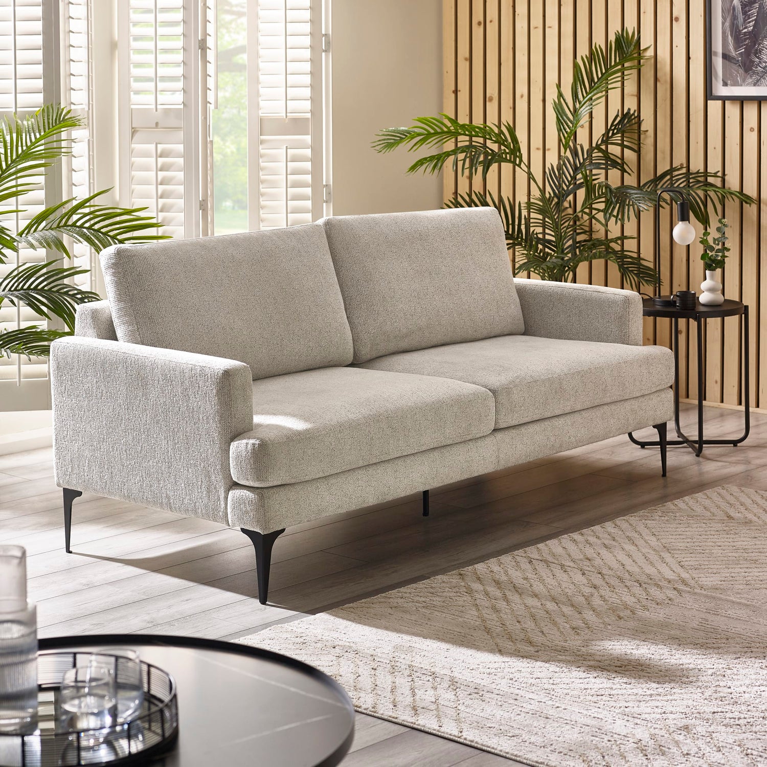 Gray sofa in a living room with plants and a side table.