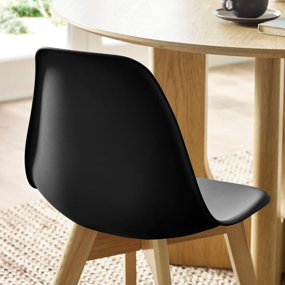 Black chair in front of a wooden table with a blurred background