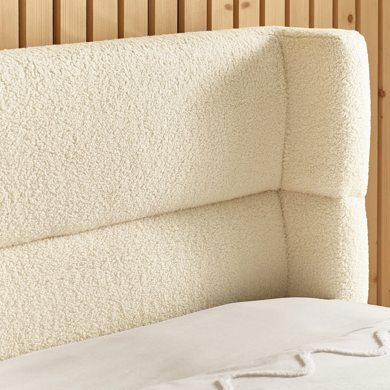 Close-up of a textured beige headboard against a wooden slatted wall.