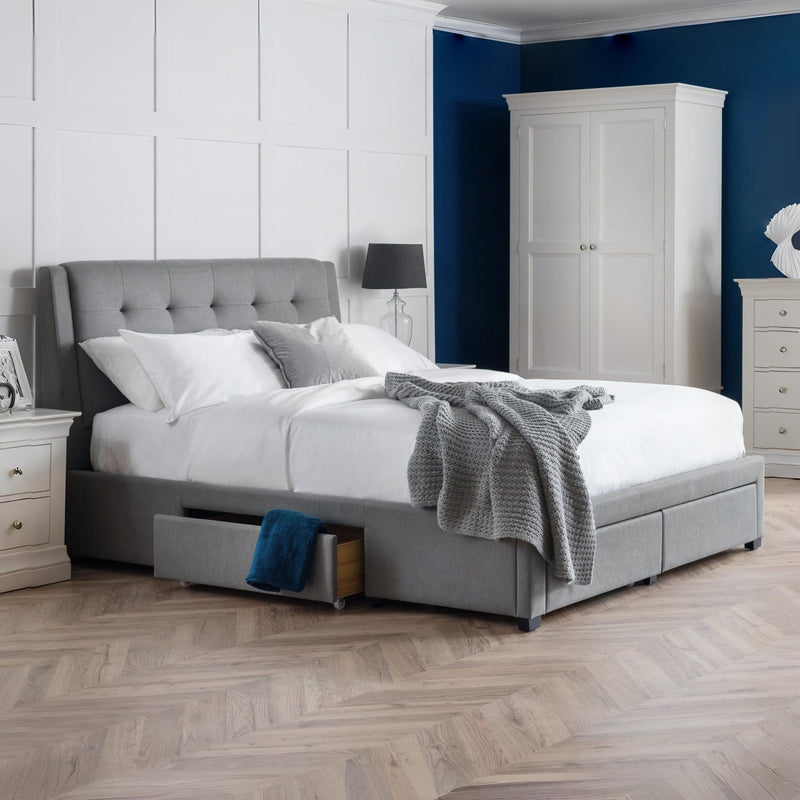 Gray upholstered bed with white bedding in a bedroom setting.