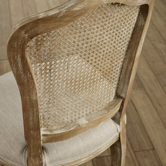 Wooden chair with wicker backrest and cushioned seat on a wooden floor.