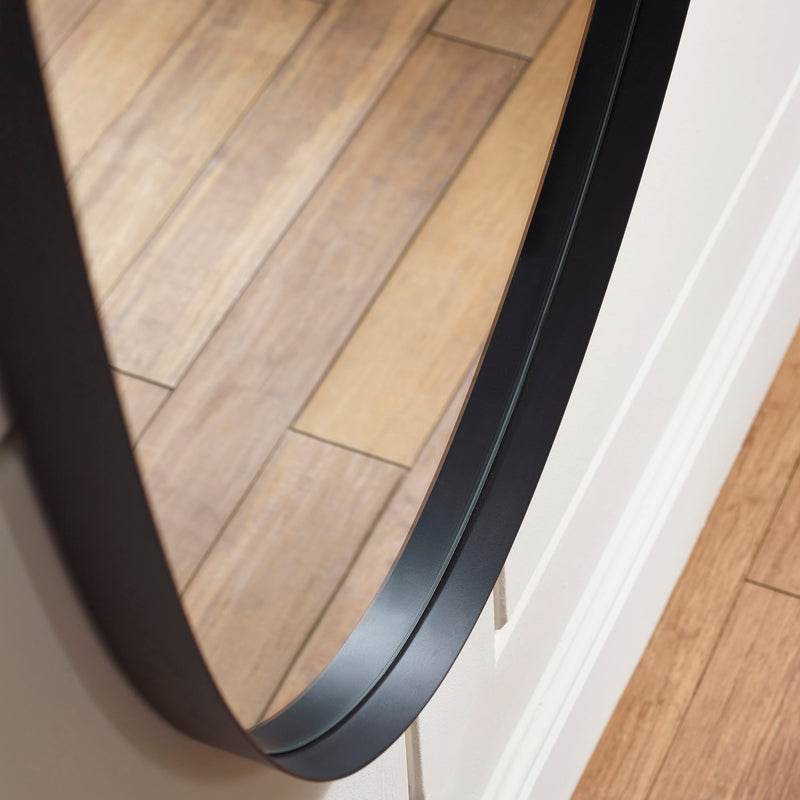 Round mirror with black frame on a wooden floor