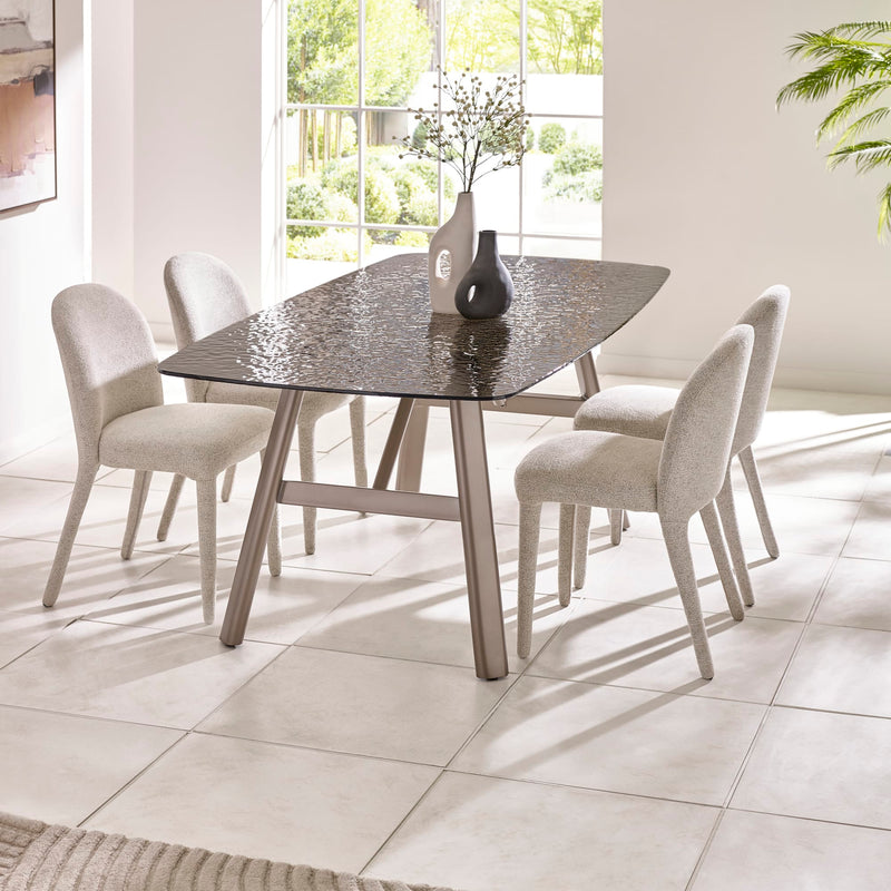 Dining table with four chairs in a bright room with large windows.