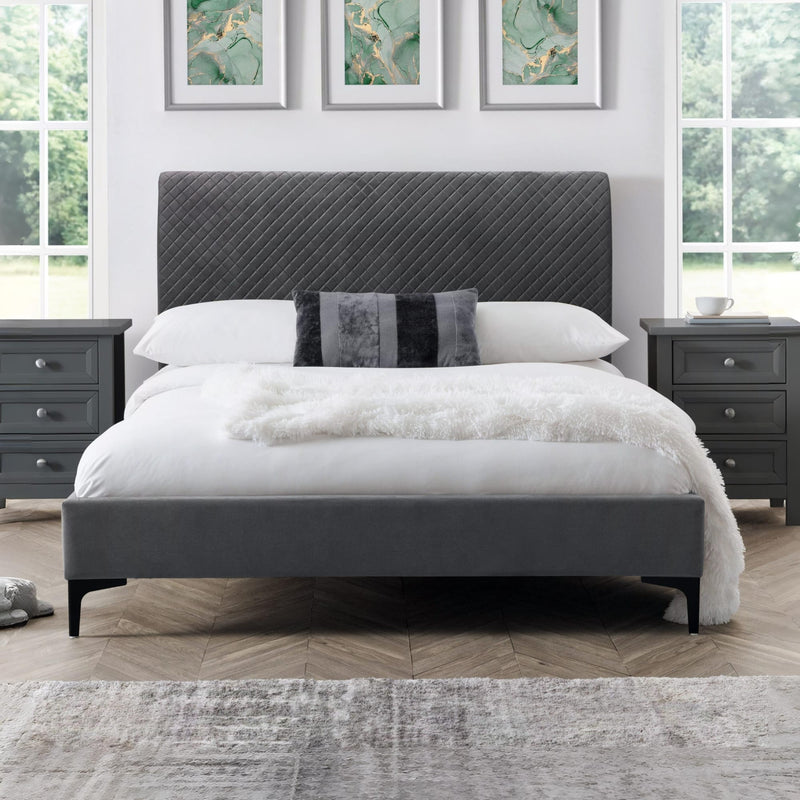 Gray upholstered bed with white bedding in a bedroom setting