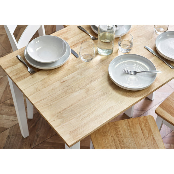 Dining table set with plates, bowls, and glasses on a wooden floor.
