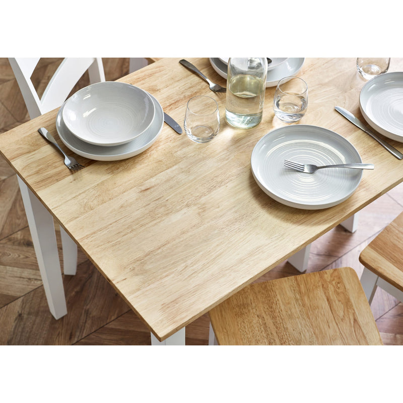 Dining table set with plates, bowls, and glasses on a wooden floor.