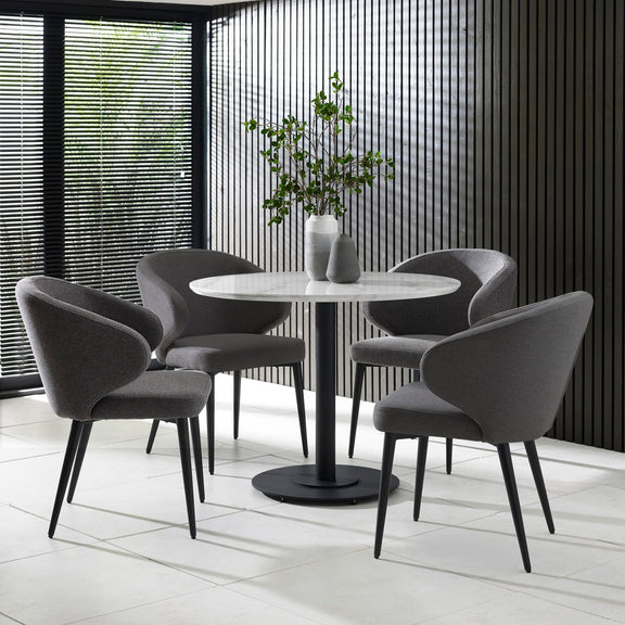 Round dining table with four gray chairs in a modern interior setting.