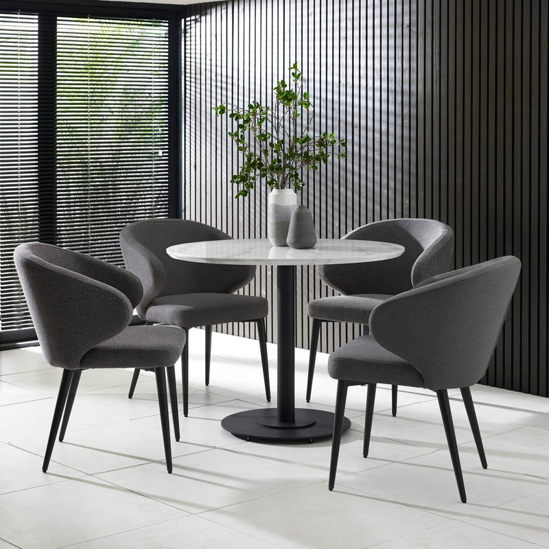 Round dining table with four gray chairs in a modern interior setting.