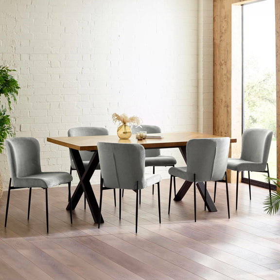 Dining room with a wooden table and gray chairs against a white brick wall.