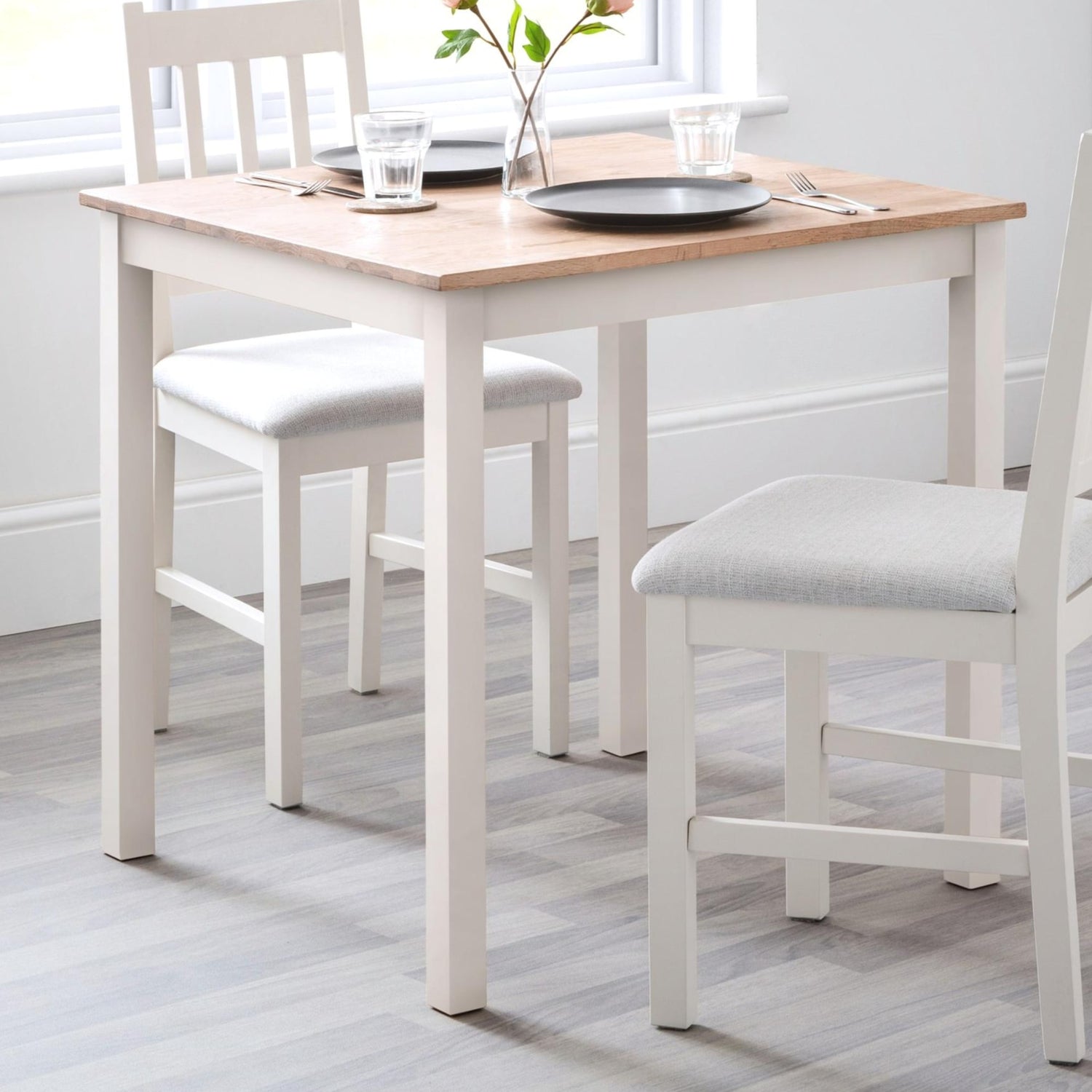 Dining table set with chairs and a vase on a wooden floor.
