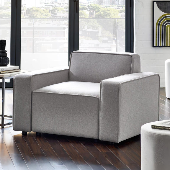 Gray armchair in a modern living room with large windows.