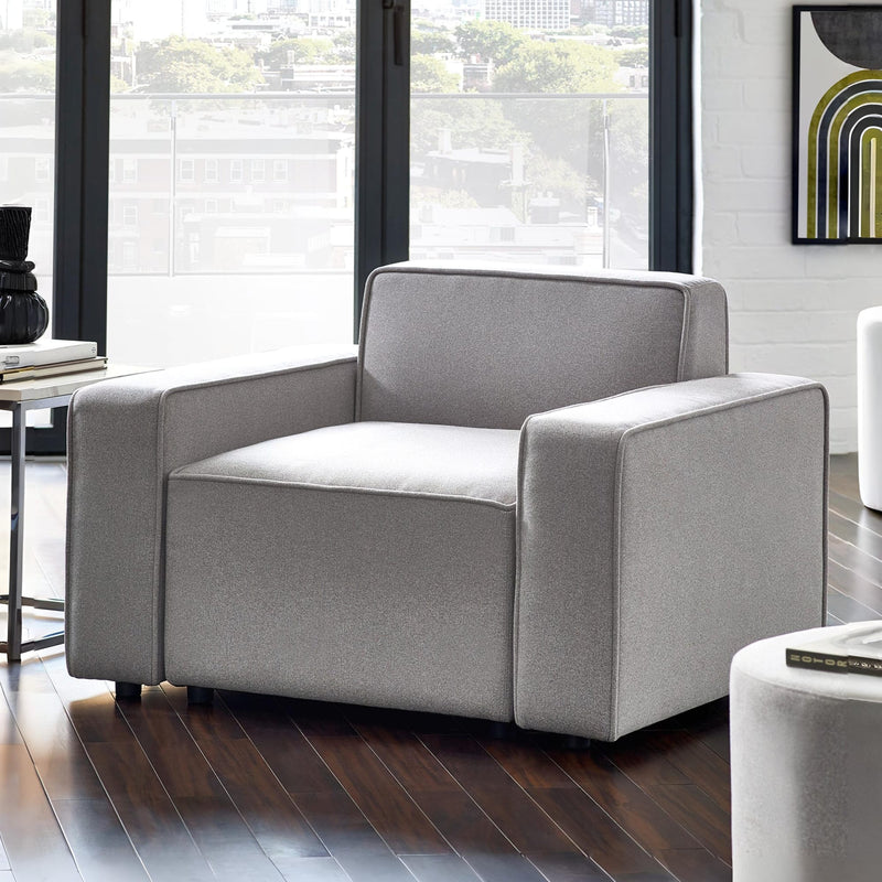 Gray armchair in a modern living room with large windows.