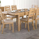 Wooden dining table set with chairs in a room with white walls and a rug.