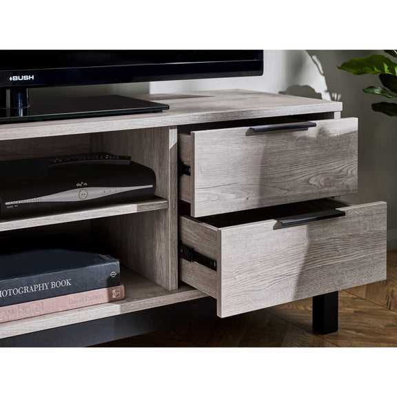 Wooden TV stand with open drawers, books, and electronic devices.