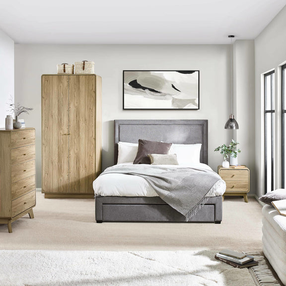Modern bedroom with gray upholstered bed, wooden wardrobe, and side table.