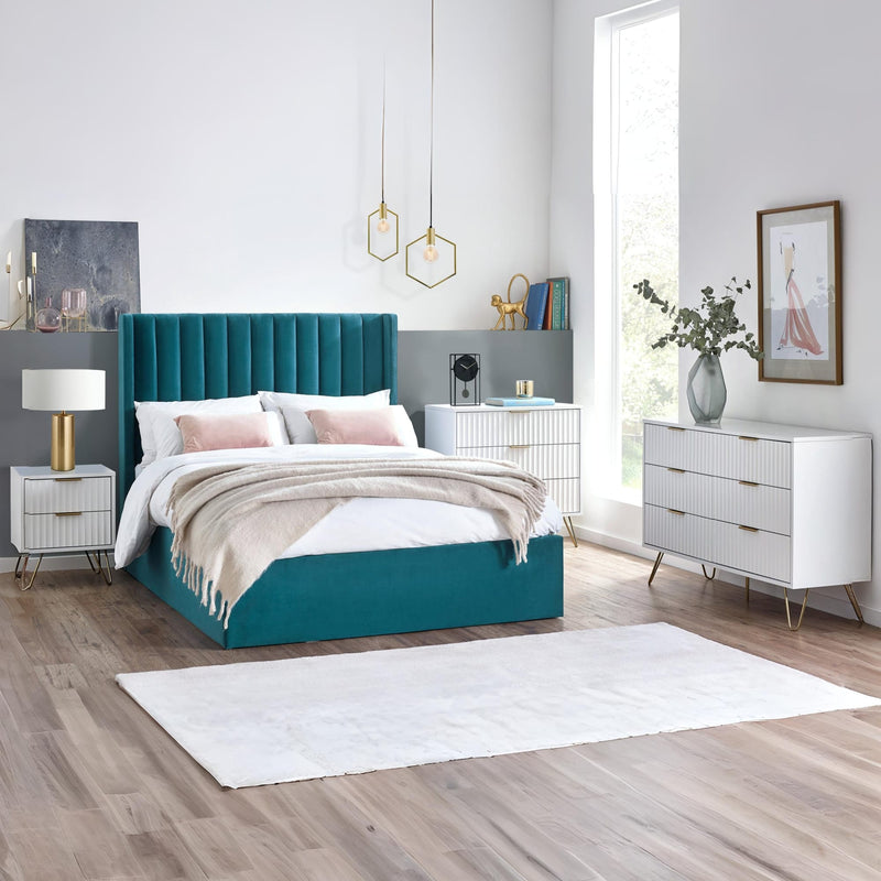 Modern bedroom with teal bed, white nightstands, and dresser.