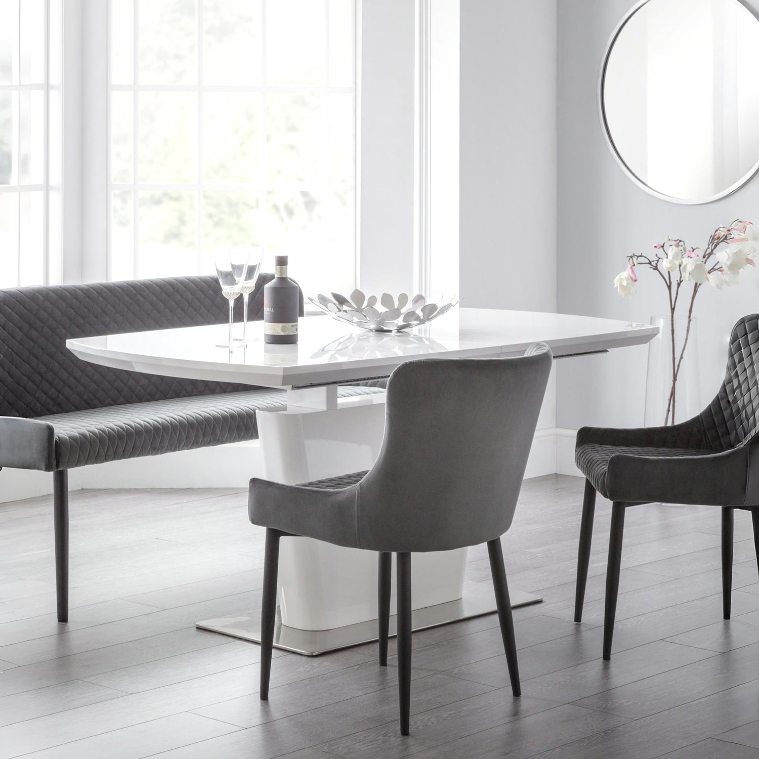 Modern dining room with a white table and gray chairs in a bright room.