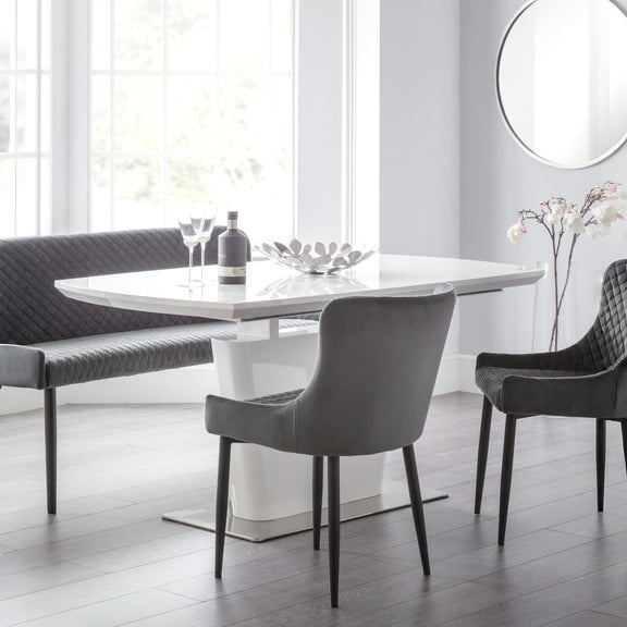 Modern dining room with a white table and gray chairs in a bright room.