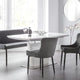 Modern dining room with a white table and gray chairs in a bright room.