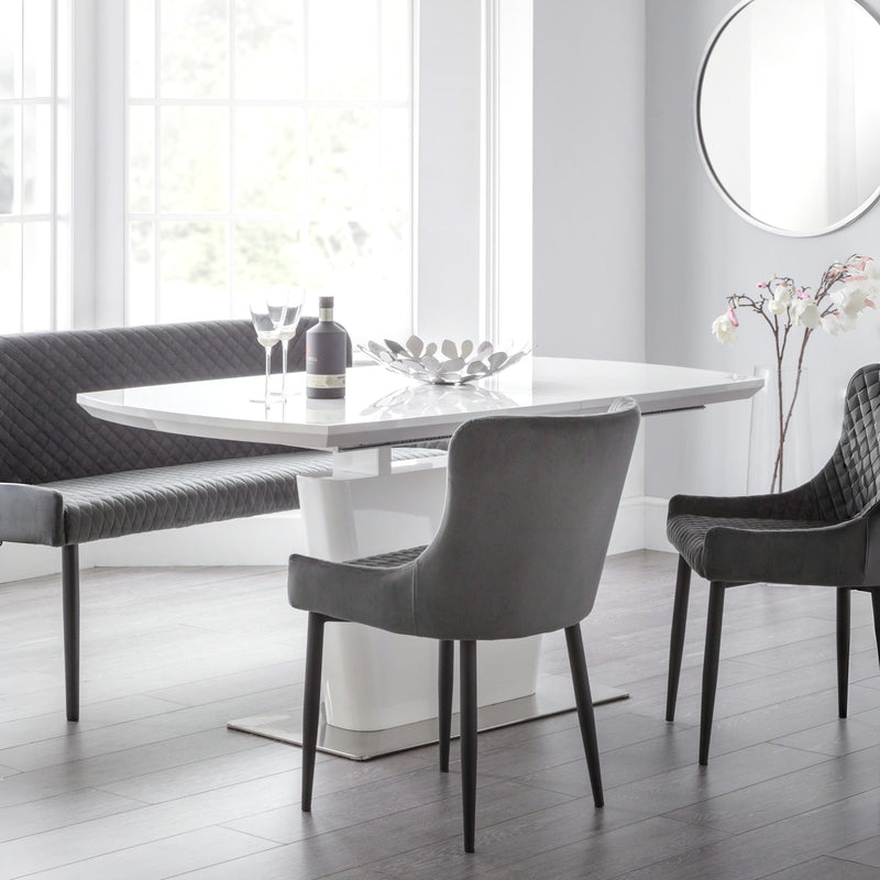 Modern dining room with a white table and gray chairs in a bright room.