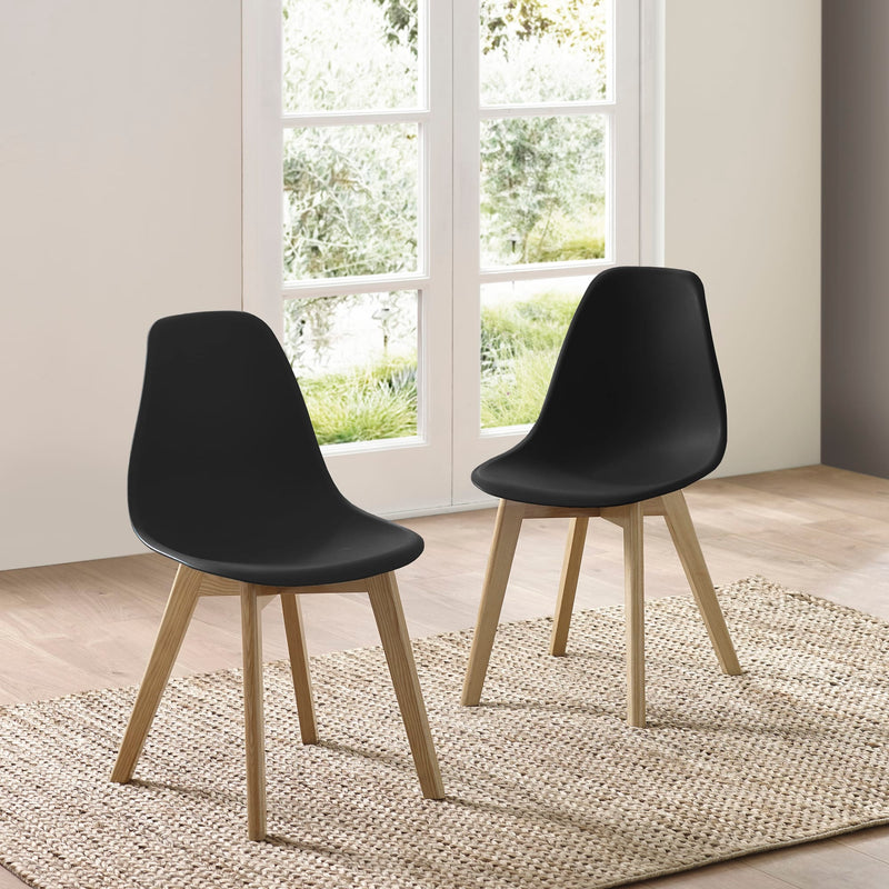 Two black chairs with wooden legs in a room with large windows.
