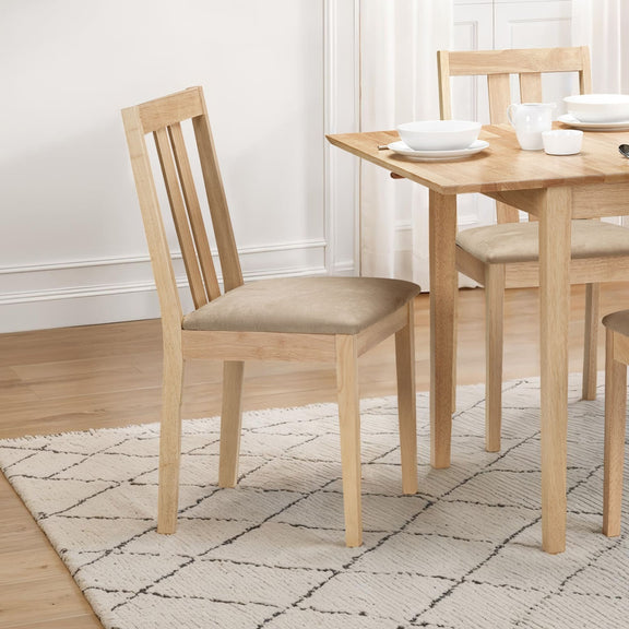 Wooden dining table with chairs on a patterned rug in a room with white walls.