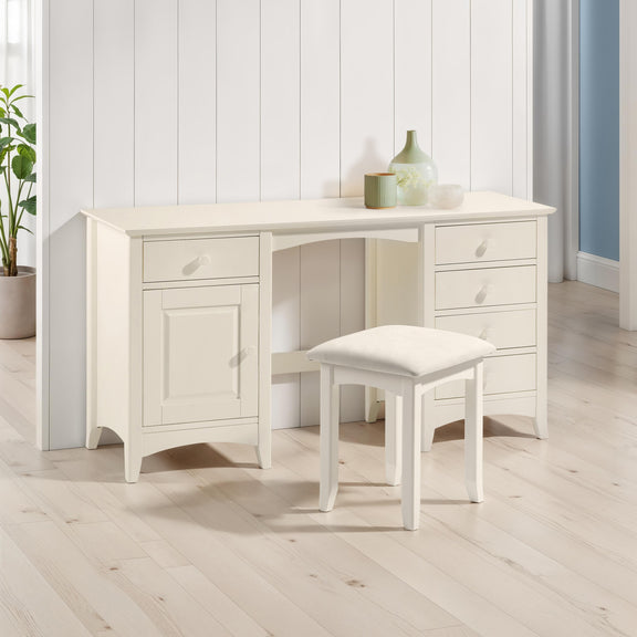 White desk with a stool in a room with light wood flooring and white walls.