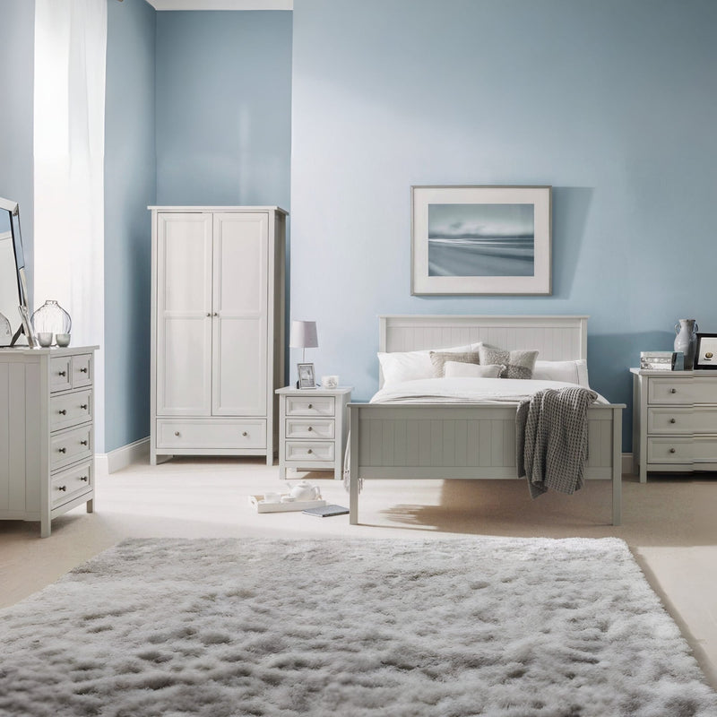 Neatly arranged bedroom with light gray furniture against a light blue wall.