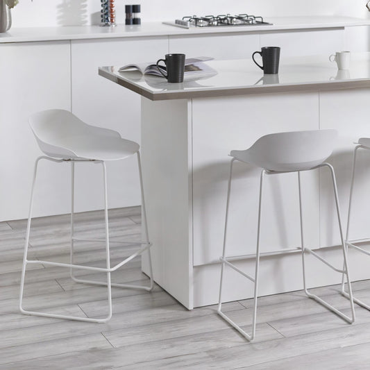 White bar stools in a modern kitchen setting with a white island.