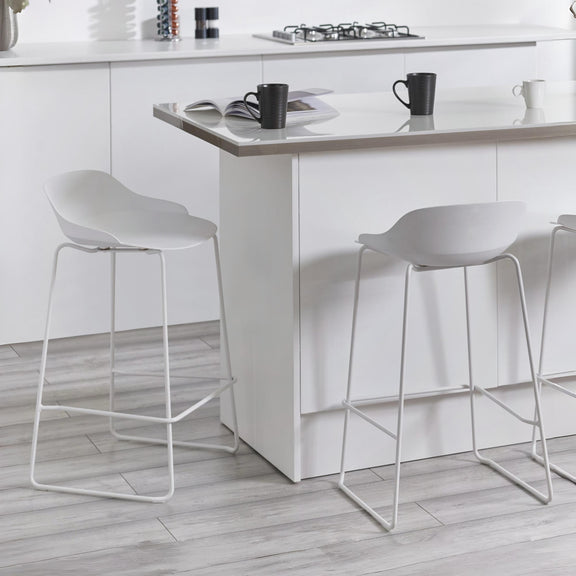White bar stools in a modern kitchen setting with a white island.