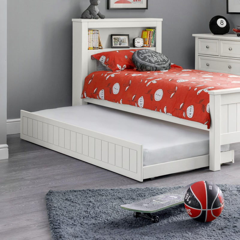 White bed with red bedding and white drawers in a room setting.
