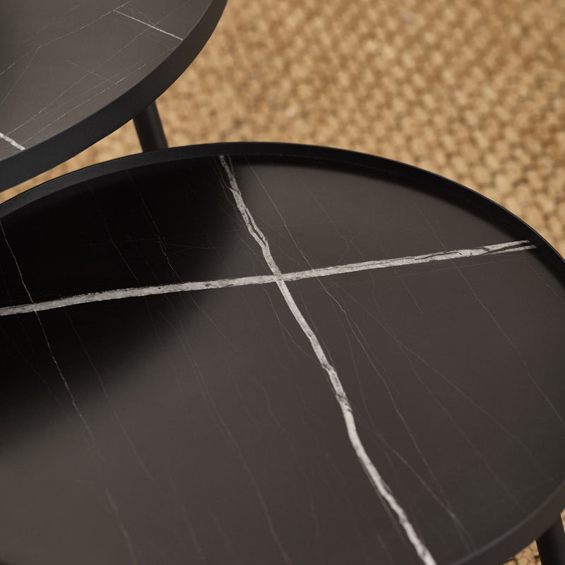 Close-up of a black marble table with visible cracks on a textured beige background