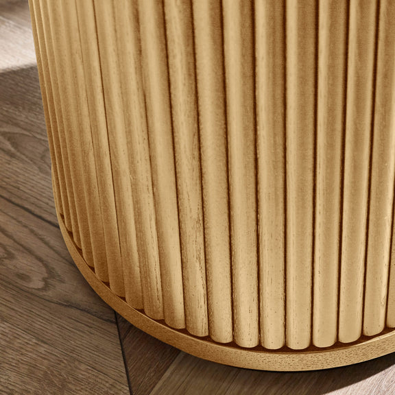 Close-up of a wooden stool with a ribbed texture on a wooden floor.