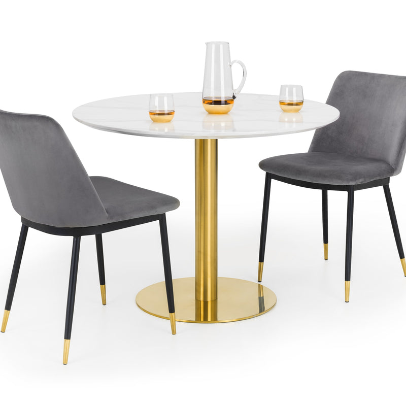 Round dining table with gold base and gray chairs on a white background