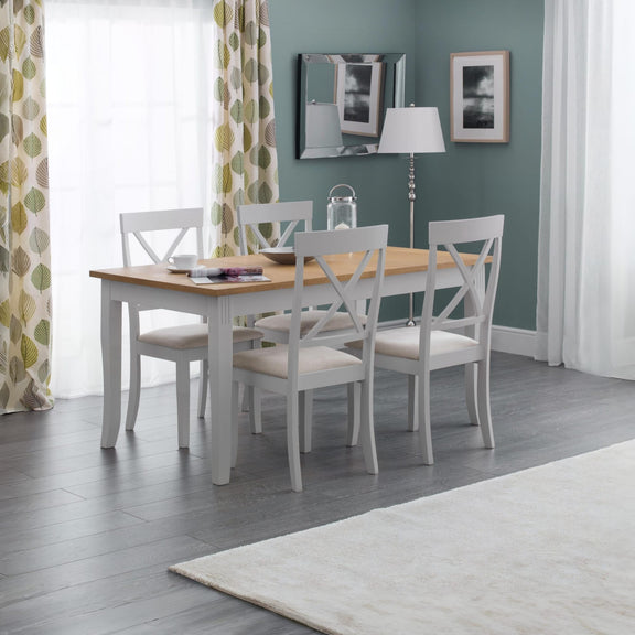 Dining room with a wooden table and white chairs against a green wall.