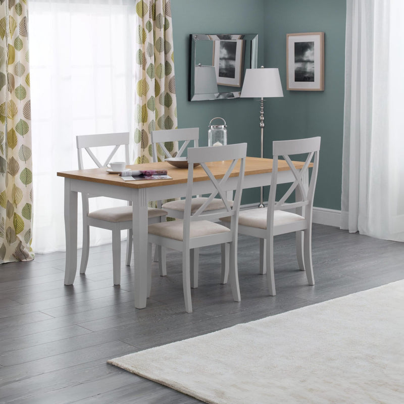 Dining room with a wooden table and white chairs against a green wall.