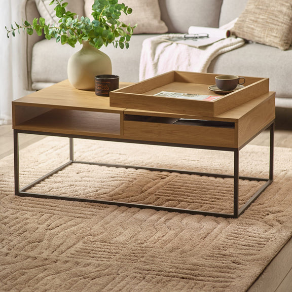 Wooden coffee table with a tray, cup, and plant in a living room setting.