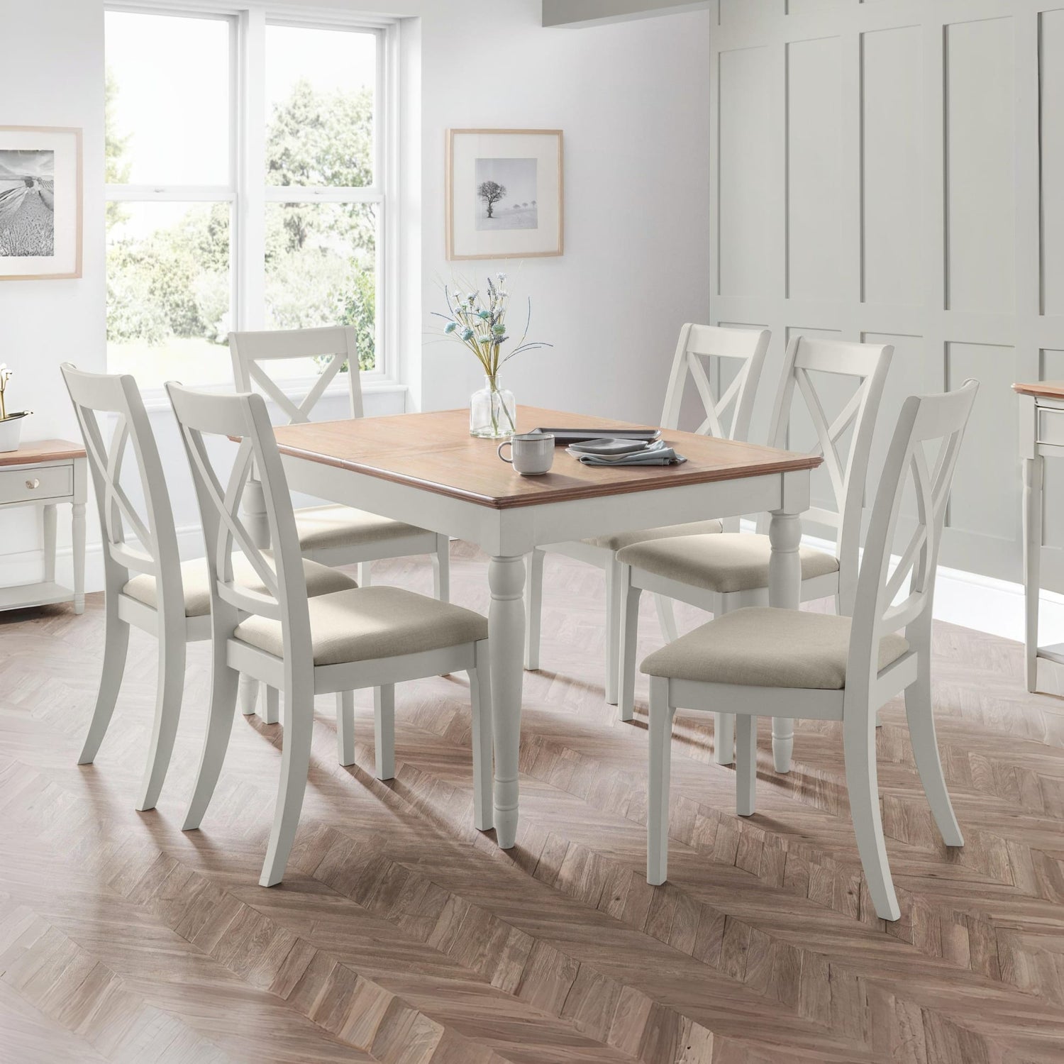 Dining room with a wooden table and white chairs on a wooden floor.