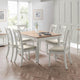 Dining room with a wooden table and white chairs on a wooden floor.